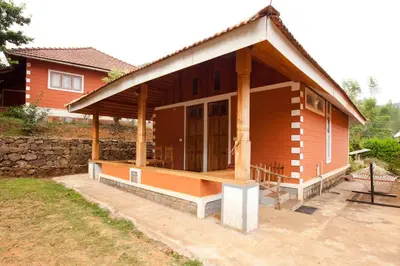 a small wooden house with a large porch at Kabbe Holidays in Madikeri