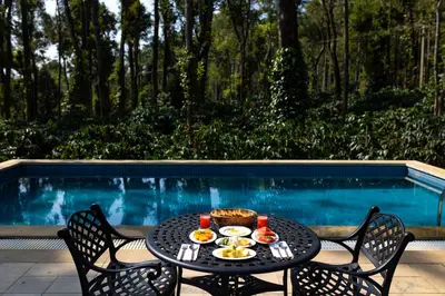 a table with food on it next to a pool at Machaan Wilderness Lodge Nagarahole in Srimangala