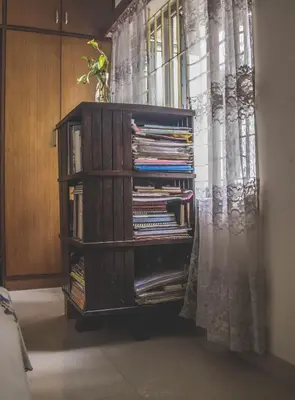 a book shelf filled with books next to a curtain at Homestay for Women in Coimbatore