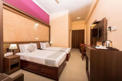 a hotel room with two beds and a television at Kallada Golden Hotel in Trichūr