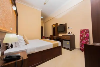 a hotel room with a bed and a television at Kallada Golden Hotel in Trichūr