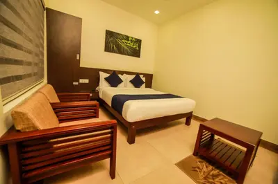 a bedroom with a bed and a chair and a table at Golden Fern Resort in Kanthalloor