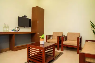 a living room with two chairs and a tv at Golden Fern Resort in Kanthalloor