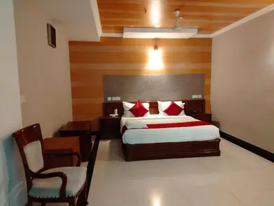 a bedroom with a bed and a desk and a chair at Hotel Jyothis Regency in Palakkad