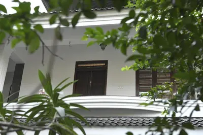 a white house with a black door and some trees at Gloria Homestay ,Thrissur - Pooram Bookings open Apr 25-27 in Trichūr