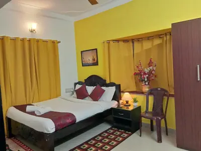 a bedroom with a bed and a table and a chair at Coorg Homeland Homestay -With Kitchenette in Madikeri
