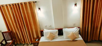 a hotel room with a bed with orange curtains at Oxxon Airport Hotel in Angamali