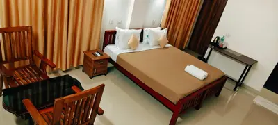 a bedroom with a bed with a chair and a table at Oxxon Airport Hotel in Angamali