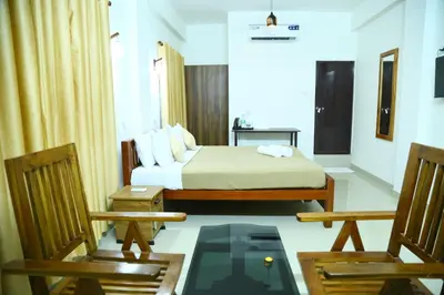 a hotel room with a bed and two chairs at Oxxon Airport Hotel in Angamali