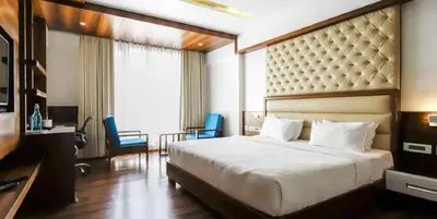 a hotel room with a large bed and a desk at Hotel Preethi International in Mysore