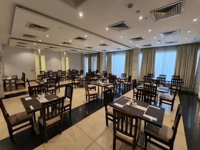 a restaurant with wooden tables and chairs and windows at Hotel Preethi International in Mysore