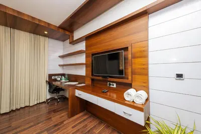 a room with a desk and a tv on a wall at Hotel Preethi International in Mysore
