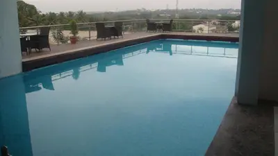 a swimming pool with blue water in a building at Mysore County Retreat in Mysore