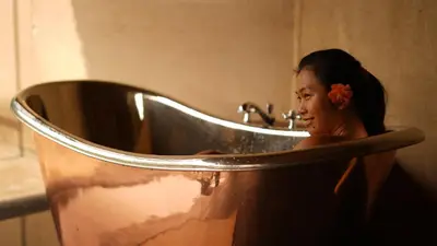 a woman sitting in a tub in a bathroom at SpiceTree Chinnar in Dhali