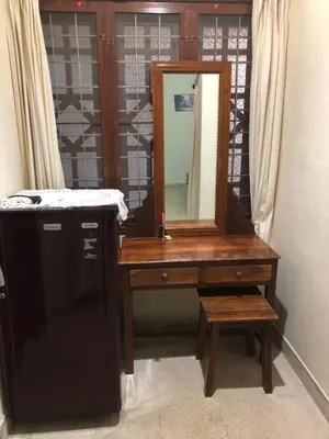 a wooden dressing table with a mirror and a stool at Ayuryogashram Heritage in Trichūr