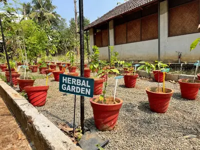 a sign in front of a garden with potted plants at Ayuryogashram Heritage in Trichūr