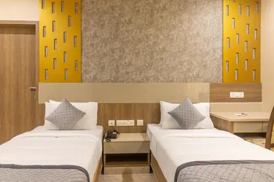 two beds in a hotel room with yellow at Rathna Residency in Erode
