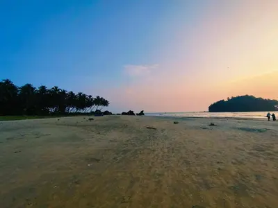 a sandy beach with trees on the horizon at 7TH HEAVEN Kannur in Chakkarakkal
