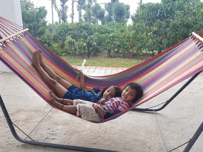 two children are laying in a hammock at THE SUVISTARA WAYANAD KERALA in Meenangadi