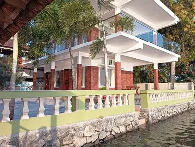 a house with a fence next to a body of water at SAGAR BEACH VILLAS Home stay in Cherai Beach