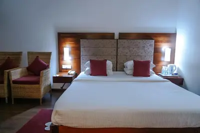 a hotel room with a large bed and a chair at Hotel Devaragam by K P Namboodiri's in Guruvāyūr