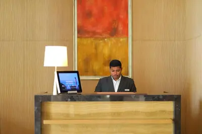 a man sitting at a desk with a laptop computer at Courtyard by Marriott Kochi Airport in Nedumbassery