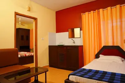 a bedroom with a bed and a table and a mirror at Vrindavan Suites Guruvayur in Guruvāyūr
