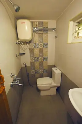 a small bathroom with a toilet and a sink at REFLECTIONS Guest House in Ooty