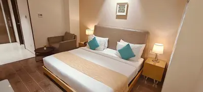 a bedroom with a large bed with blue pillows at The Mayberry -A Bergamont Group of Hotels in Tiruppūr