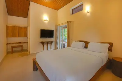 a bedroom with a large white bed and a television at StayVista at Tall Silver with Infinity Pool & Breakfast -2BR in Madikeri