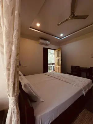 a bedroom with a large bed with a ceiling fan at Maleyam Homestay Riverside in Kozhikode