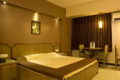 a bedroom with a bed and a table and a chair at Comfort Hotels in Coimbatore