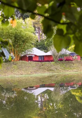 a red barn in the middle of a field at Kadkani River Resort Coorg in Siddapur