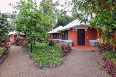 a red house with a red door and trees at Kadkani River Resort Coorg in Siddapur