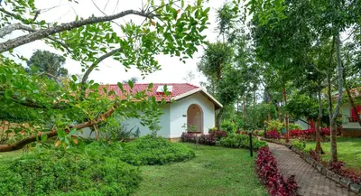 a house with a red roof in a garden at Kadkani River Resort Coorg in Siddapur