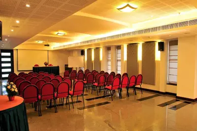 a conference room with red chairs and a podium at Copper Folia in Kozhikode
