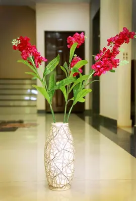 a vase with red flowers in it on a table at Hotel Wayanad Square in Mananthavady