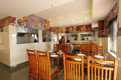 a restaurant with wooden tables and chairs and a counter at Hotel Wayanad Square in Mananthavady