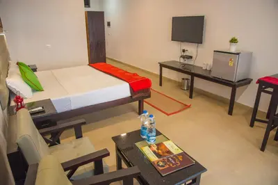 a room with a bed and a table and a tv at 36 Palms Residency - Sea View Villa in Cochin
