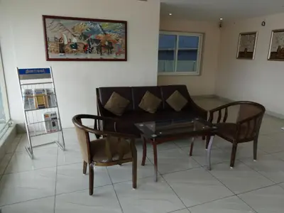 a living room with a couch and a table and chairs at Hotel Sky Lite in Coimbatore