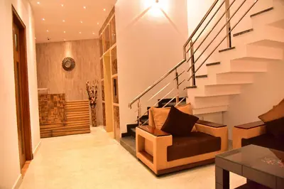 a living room with a staircase and a chair at Le Oak Inn in Mysore
