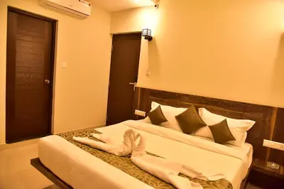a bedroom with a bed with white sheets and pillows at Le Oak Inn in Mysore