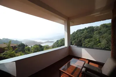 a balcony with a chair and a glass table at CONTOUR ISLAND RESORT & SPA , wayanad in Tariyod