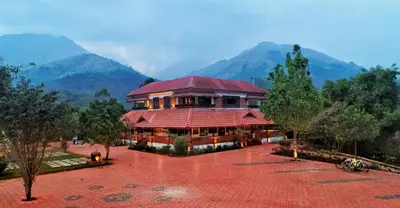 a building with a red roof with mountains in the background at CONTOUR ISLAND RESORT & SPA , wayanad in Tariyod