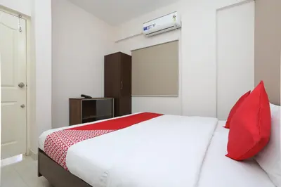 a bedroom with a white bed with a red pillow at Super Hotel O Indra Comforts in Belagula