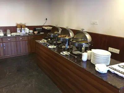 a buffet line in a restaurant with plates and food at The Majestic Crown in Ooty