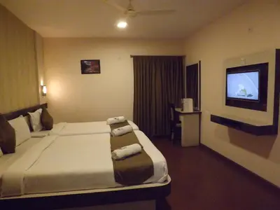a hotel room with a bed and a television at The Majestic Crown in Ooty