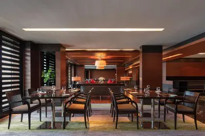 a restaurant with tables and chairs and a bar at Le Meridien Coimbatore in Coimbatore