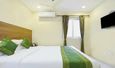 a bedroom with a bed with green pillows and a window at Itsy Hotels Jansi Residency in Coimbatore