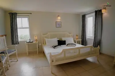 a bedroom with a white bed and two windows at Yellow Tulip Hill Side Luxury Villa by LexStays in Coonoor